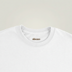 Gros plan du col et de l’étiquette du T-shirt L’ombre des Géants couleur White sur fond studio gris chaud uniforme