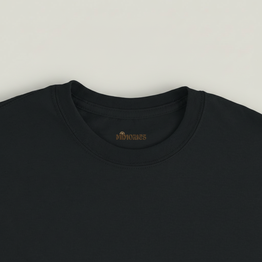 Gros plan du col et de l’étiquette du T-shirt Rivières & Falaises couleur Black sur fond studio gris chaud uniforme